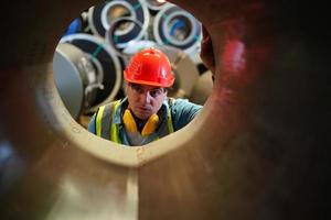 el capataz de los trabajadores de la industria o el trabajo de los trabajadores en el sitio de la fábrica revisan la máquina o los productos en el sitio. ingeniero o técnico revisando material o máquina en planta. industrial y fábrica. foto