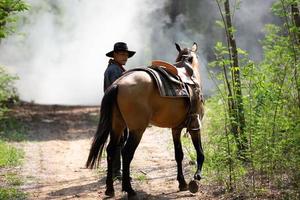 Cowboy on horseback against a beautiful sunset, cowboy and horse at first light, mountain, river and lifestyle with natural light background photo