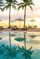 Umbrella and chair around swimming pool in hotel resort with sunrise in morning photo