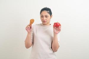 Mujer asiática con pollo frito y manzana en la mano foto