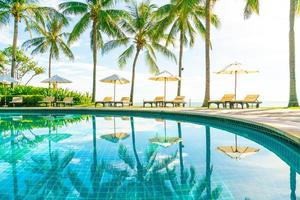 Beautiful umbrella and chair around swimming pool in hotel and resort photo