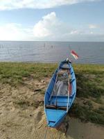 Small ship on the beach with a red and white flag at the stern photo