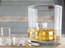 whiskey glasses with ice cubes isolated on old wood photo