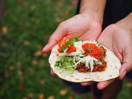 Taco Mexican food on hands young woman while standing in a garden photo