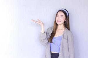 Beautiful young Asian woman long brown hair in a people shirt is acting hand shows as presenting something on the white background. photo