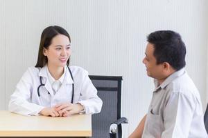 Young Asian professional female doctor good mood smile suggests health solutions to elderly male patients in the hospital examination room.