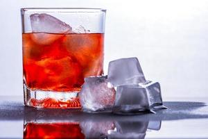 Glass of whiskey and ice on a glass table photo