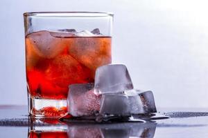 Glass of whiskey and ice on a glass table photo