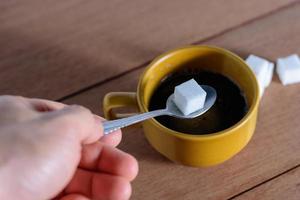 The hand is filling the sugar into the coffee. photo