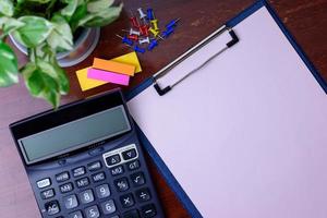 Calculator, file, pencil and office supplies. Placed beside a tree on a wooden table. photo