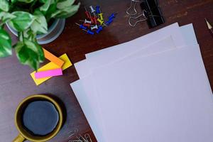 Coffee, file, pencil and office supplies. Placed beside a tree on a wooden table. photo