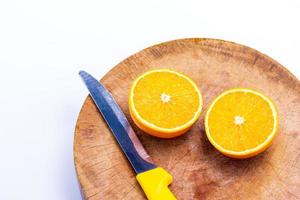 la naranja es la mitad de la bola y los cuchillos colocados en la tabla de cortar sobre el fondo blanco foto