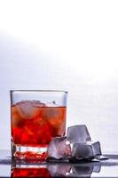 Glass of whiskey and ice on a glass table