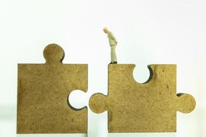 Business, Teamwork, Planning and Work Concept. Close up of of businessman miniature figure people standing and looking to wooden jigsaw piece with copy space. photo