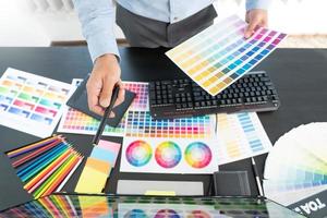 diseñador gráfico creativo que elige la escala de colores para editar obras de arte mientras trabaja en la oficina. foto