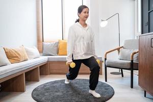 mujer deportiva en ropa deportiva está sentada en la alfombra en casa en la sala de estar haciendo ejercicio, saludable y concepto de estilo de vida.