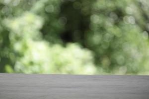 Empty wooden table top planks with beautiful nature blurred green leaf background under sunlight photo