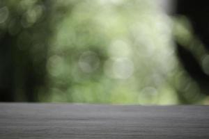 Empty wooden table top planks with beautiful nature blurred green leaf background under sunlight photo