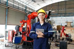 joven profesional empleada de una fábrica industrial que trabaja con piezas de máquinas, revisando y probando equipos industriales y brazos robóticos en grandes plantas de fabricación y cables electrónicos eléctricos foto