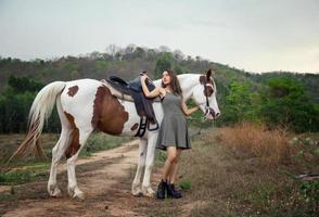 mujer joven con su caballo en la luz del atardecer. fotografía al aire libre con una modelo de moda. estado de ánimo de estilo de vida foto