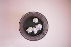 crumpled paper ball in a bin on a light purple background photo