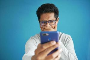 triste joven usando un teléfono inteligente en interiores foto