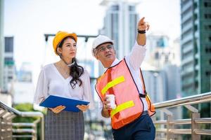 el ingeniero y la mujer de negocios revisando el portapapeles en el edificio del sitio de construcción. el concepto de ingeniería, construcción, vida urbana y futuro. foto