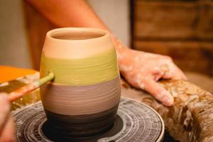 Potter working on potters wheel with clay. Process of making ceramic tableware in pottery workshop. photo