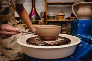 Potter working on potters wheel with clay. Process of making ceramic tableware in pottery workshop. photo