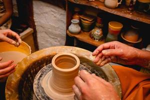 Potter working on potters wheel with clay. Process of making ceramic tableware in pottery workshop.