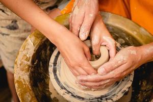 Potter working on potters wheel with clay. Process of making ceramic tableware in pottery workshop. photo