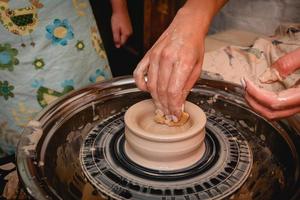 Potter working on potters wheel with clay. Process of making ceramic tableware in pottery workshop. photo