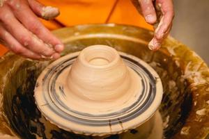 Potter working on potters wheel with clay. Process of making ceramic tableware in pottery workshop. photo