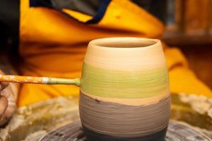 Potter working on potters wheel with clay. Process of making ceramic tableware in pottery workshop. photo