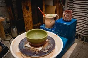 Potter working on potters wheel with clay. Process of making ceramic tableware in pottery workshop. photo