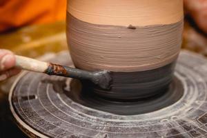 Potter working on potters wheel with clay. Process of making ceramic tableware in pottery workshop. photo