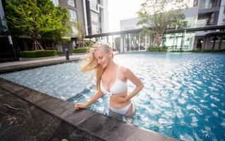 woman in white bikini tanning by the pool photo