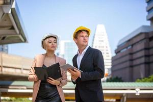 el ingeniero y la mujer de negocios revisando el portapapeles en el edificio del sitio de construcción. el concepto de ingeniería, construcción, vida urbana y futuro. foto