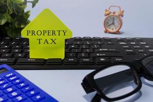 texto del impuesto a la propiedad en papel amarillo en un escritorio. concepto de propiedad inmobiliaria. foto