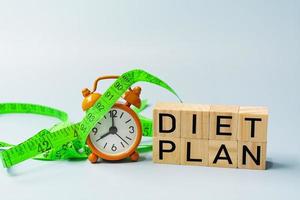 Diet plan text on wooden block cube with measure tap and orange clock. photo