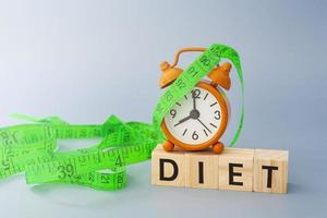 Diet text on wooden block cube with measure tap and orange clock. photo