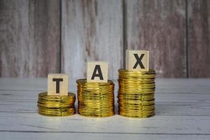 Tax text on wooden blocks and coins on table. Tax concept. photo