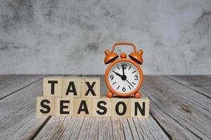 Tax season text on wooden blocks and alarm clock set at 10 o'clock on table. photo