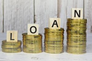 Loan text on wooden blocks with gold coins on a wooden table. Mortgage concept. photo