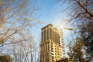 construcción de un edificio de apartamentos de varios pisos en la ciudad. una grúa cerca de un rascacielos. edificio, mudanza a un nuevo piso, hipoteca, alquiler y compra de bienes inmuebles. copie el espacio foto