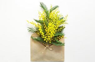 A yellow bouquet of mimosa and a gift box and a kraft paper bag. Greeting card for International Women's Day, Spring Festival, March 8, Easter. Copy space photo
