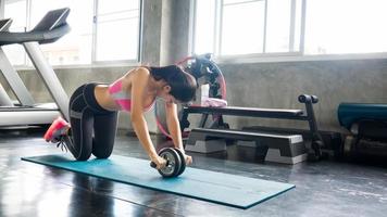 pareja atleta deportistas haciendo ejercicio con rueda de rodillos abs para fortalecer su músculo abdominal en el gimnasio. foto