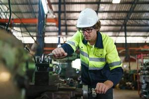 Industrial engineer or worker wearing a helmet while standing in a heavy industrial factory. The Maintenance looking of working at industrial machinery and check security system setup in factory. photo