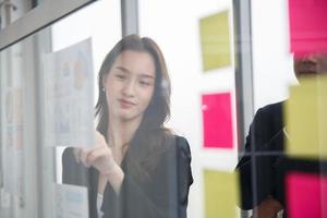 Young Asian businesswoman pointing on white board in meeting room. Young start-up business team working in meeting room photo