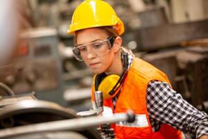 el trabajo de la trabajadora en el sitio de la fábrica revisa la máquina o los productos en el sitio. ingeniero o técnico revisando material o máquina en planta. industrial y fábrica. foto